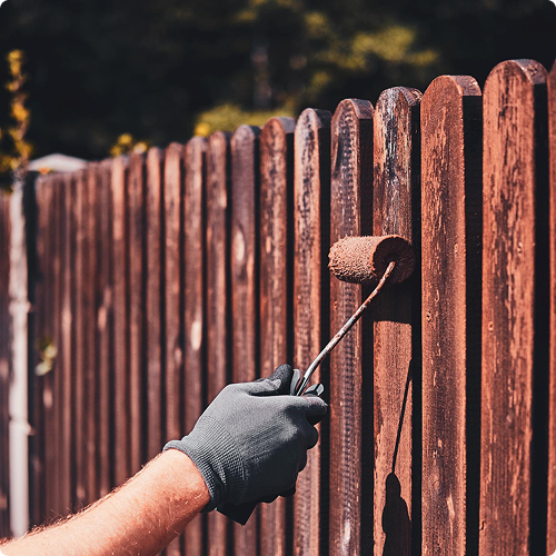 Wooden fence being stained with a roller