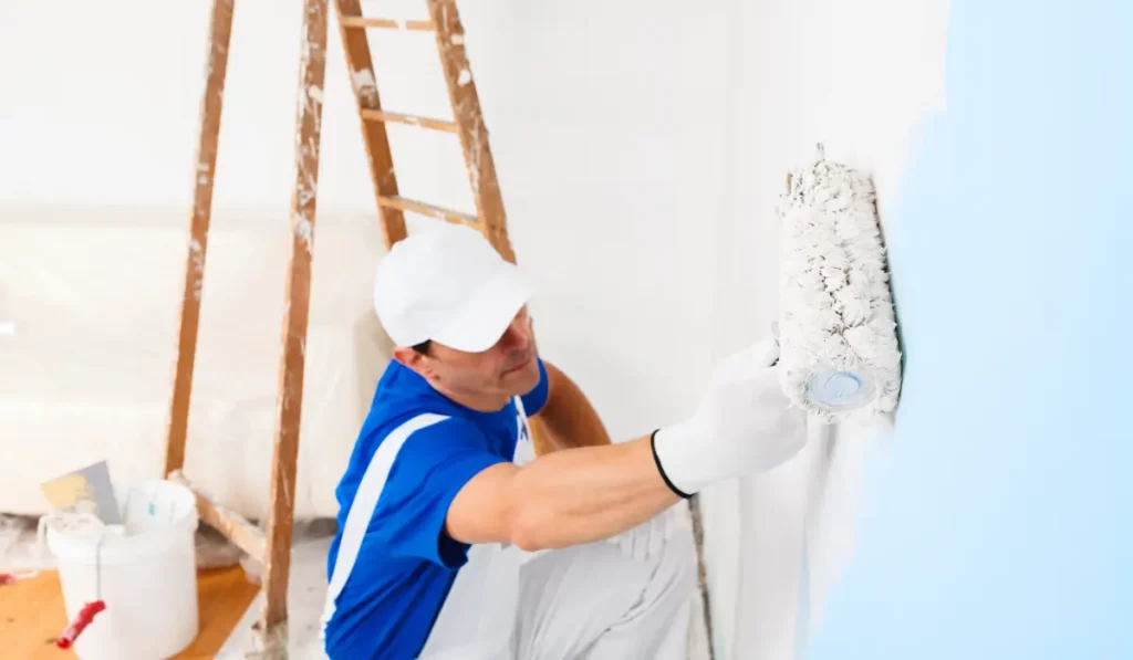 Professional painter applying safe and low-odor paints to an interior wall in a Naperville home using a roller brush, with no visible fumes or protective mask.