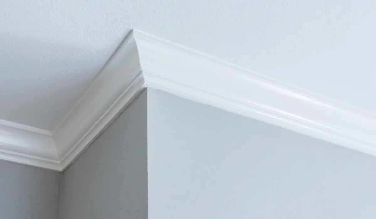 Crown molding painting showing clean trim and ceiling transition under lighting that reveals imperfections