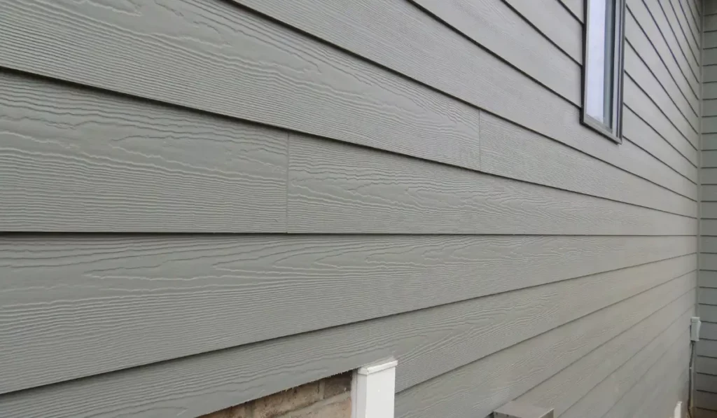 Close-up of Hardie Board fiber cement siding showing wood grain texture and seams, used to evaluate surface condition before siding painting.